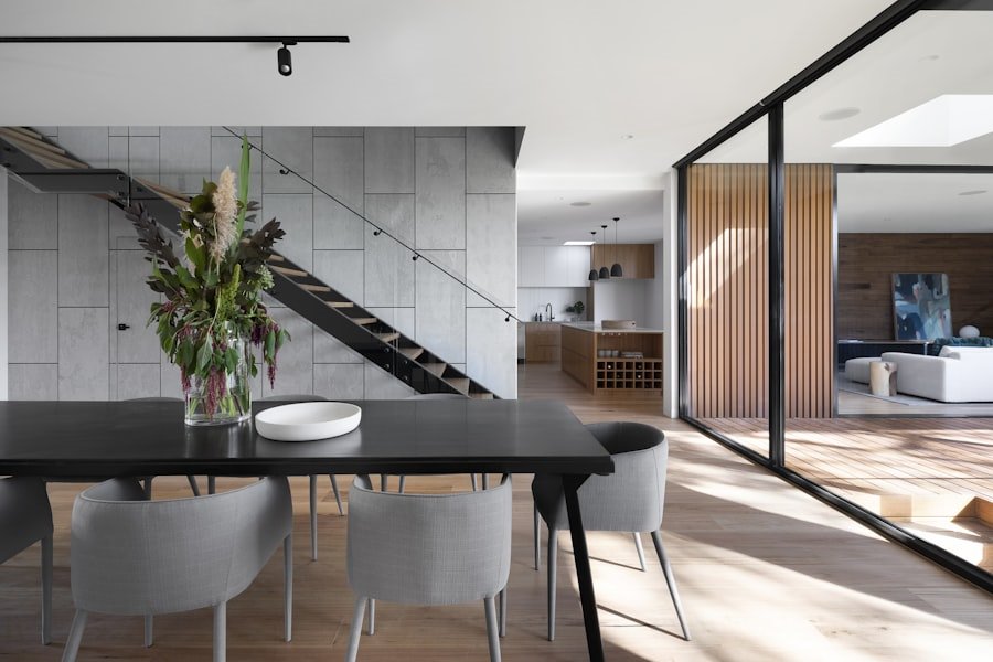 Dining space with a black stone table beside a glazed steel stair