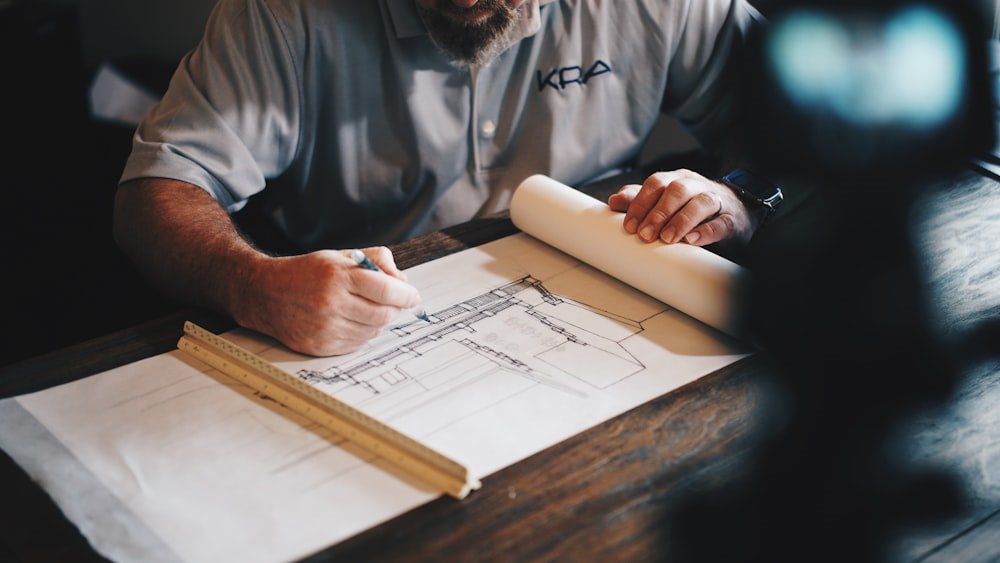 Architect sketching a building section beside a rolled drawing